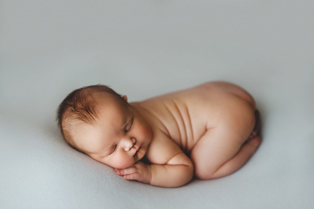 photo of newborn baby sleeping on blue backdrop