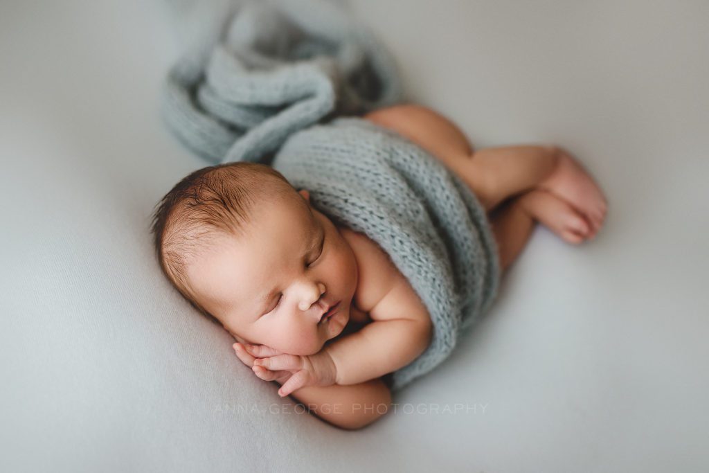 posed newborn photo of baby boy on blue background