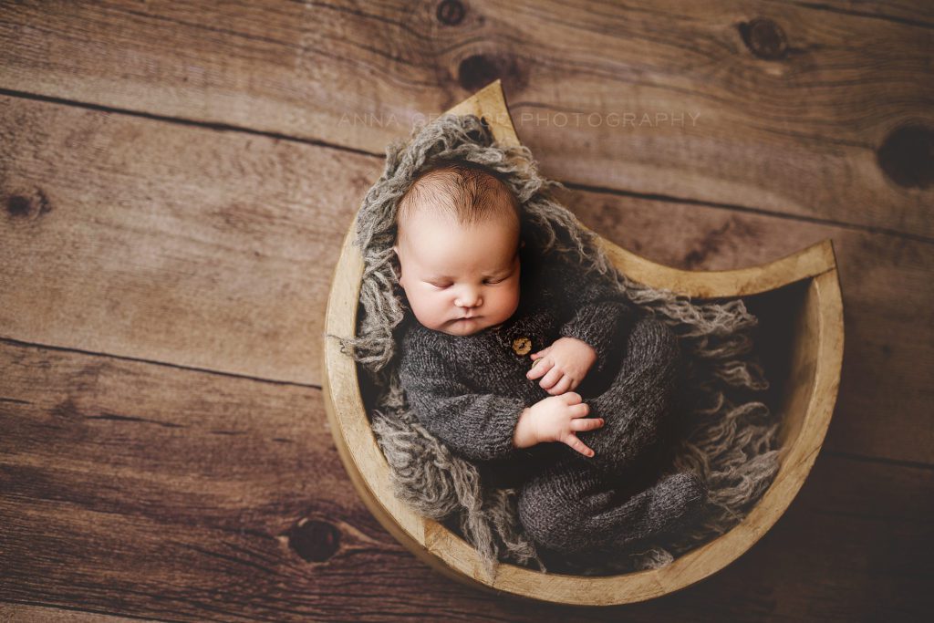 photo of newborn baby in moon shaped wooden bowl