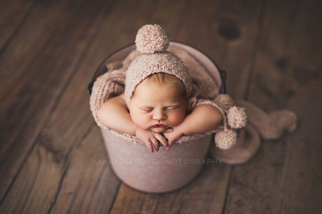 newborn baby girl in a pink bucket, photographed in Madison WI