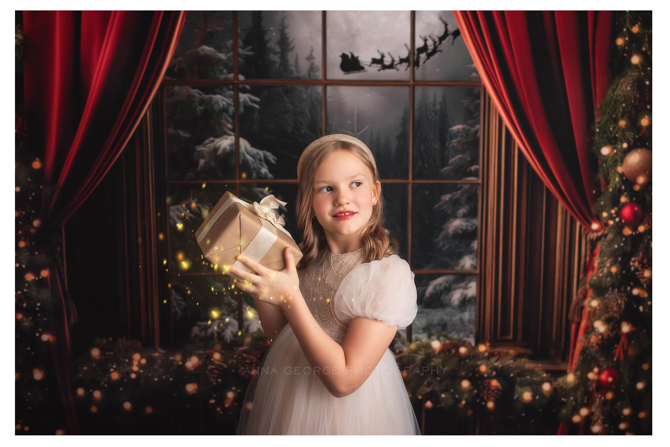 christmas mini photography sessions in Madison WI girl holding present on decorated backdrop